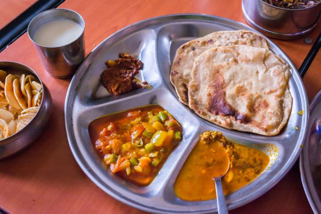 Traditional steel thali with roti, dal, vegetable curry and lassi