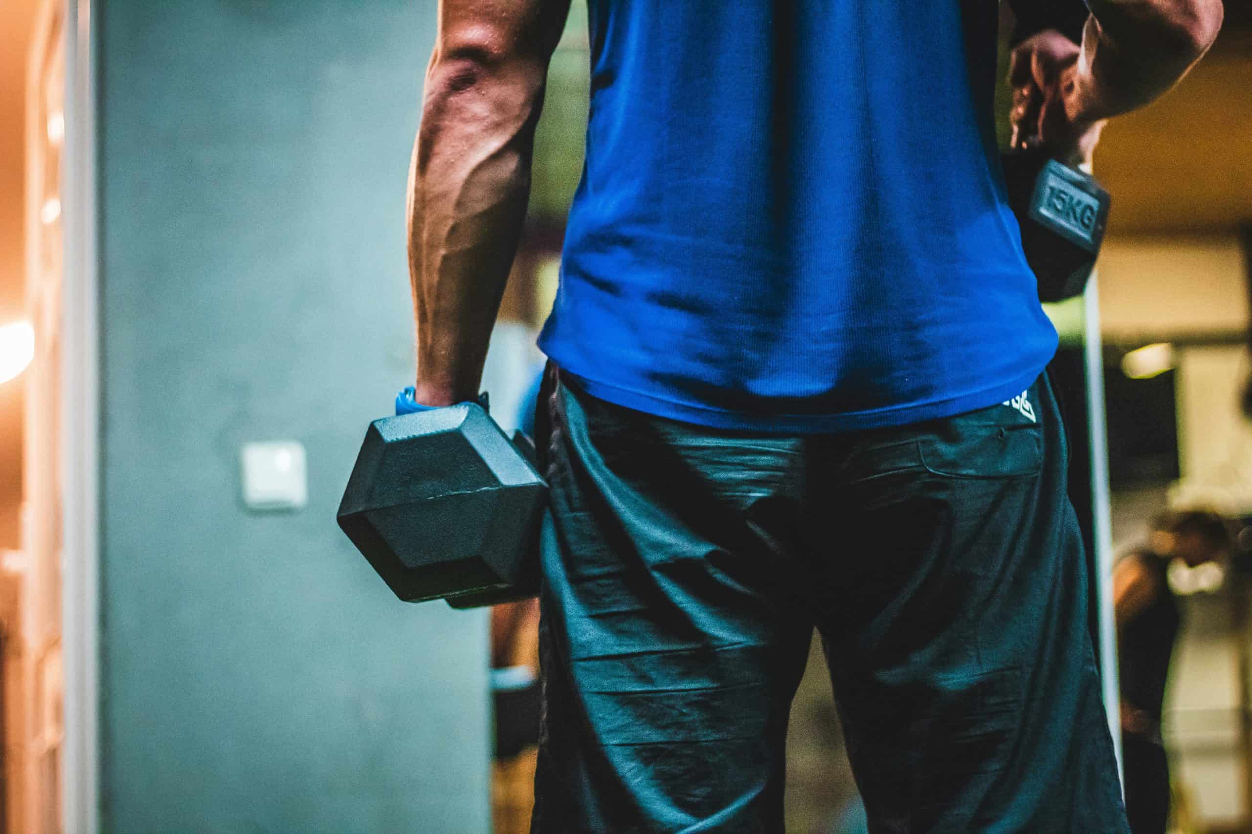 Man holding a dumbbell at his side in a gym