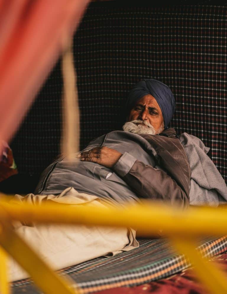 Man in a turban resting in bed under a blanket